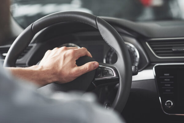 man's big hands on a steering wheel while driving a car.