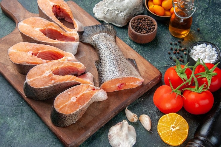 top view of fresh raw fishes on wooden cutting board oil bottle fresh foods on dark mix colors table 179666 18226