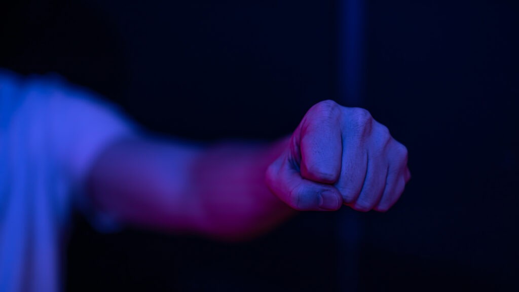 close up of a male clenched fist in a dark room lighting.