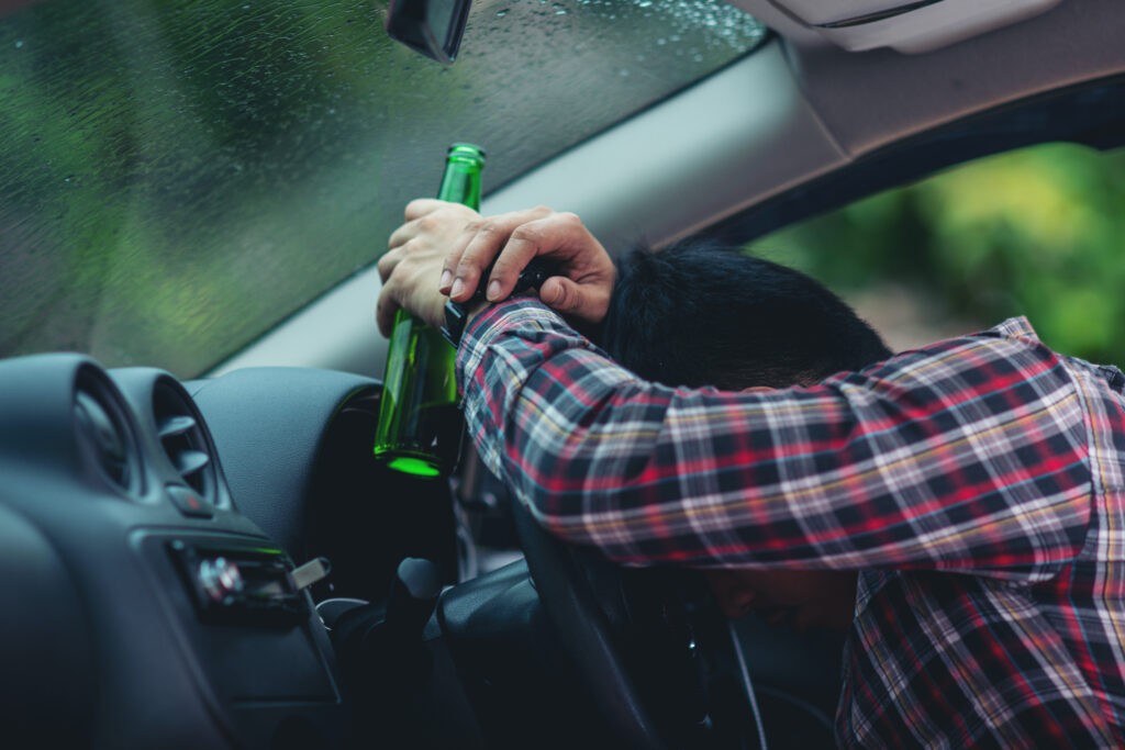 hansome man holding beer bottle while driving a car
