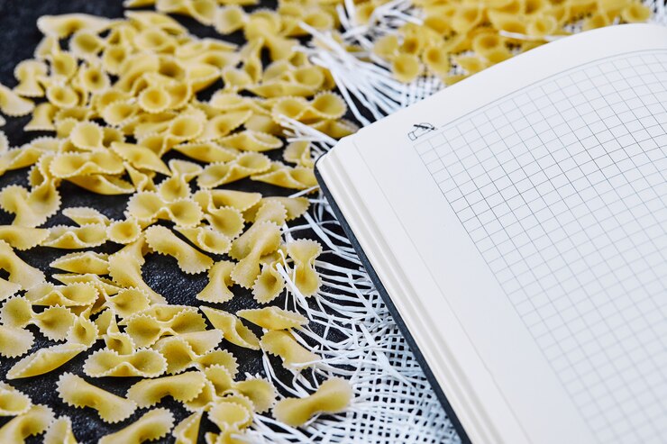 scattered raw pasta around notebook on blue background 114579 84566