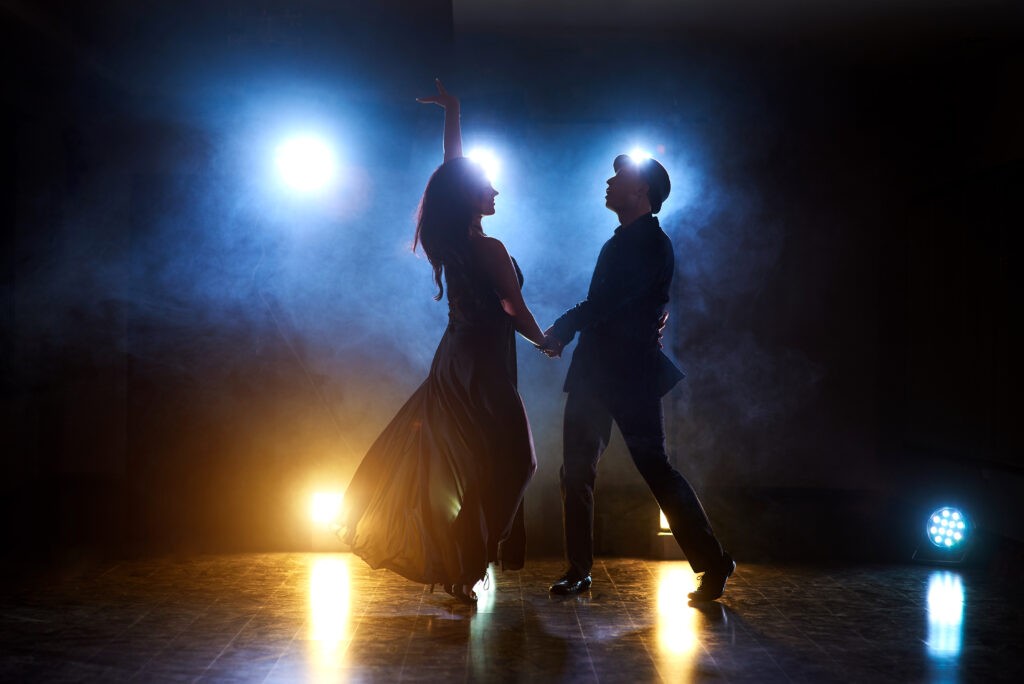 skillful dancers performing in the dark room under the concert light and smoke. sensual couple performing an artistic and emotional contemporary dance